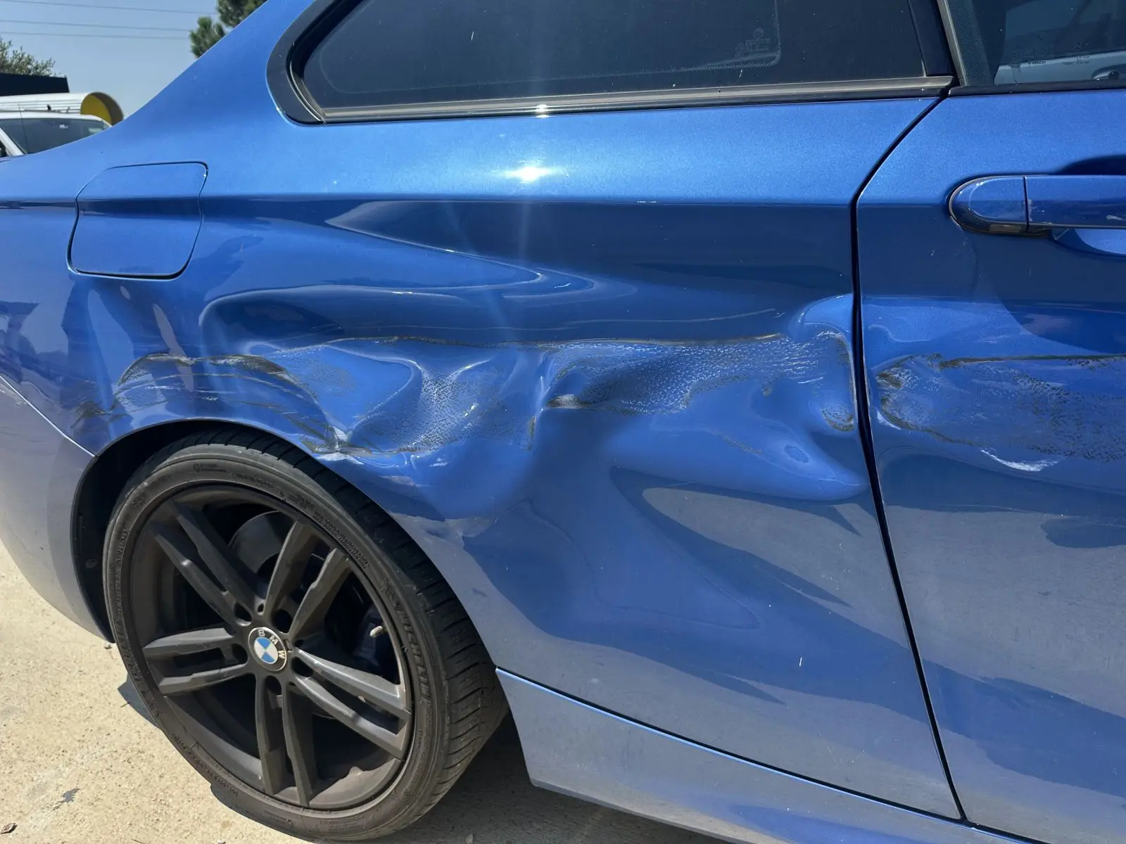 Blue BMW with a dented rear quarter panel