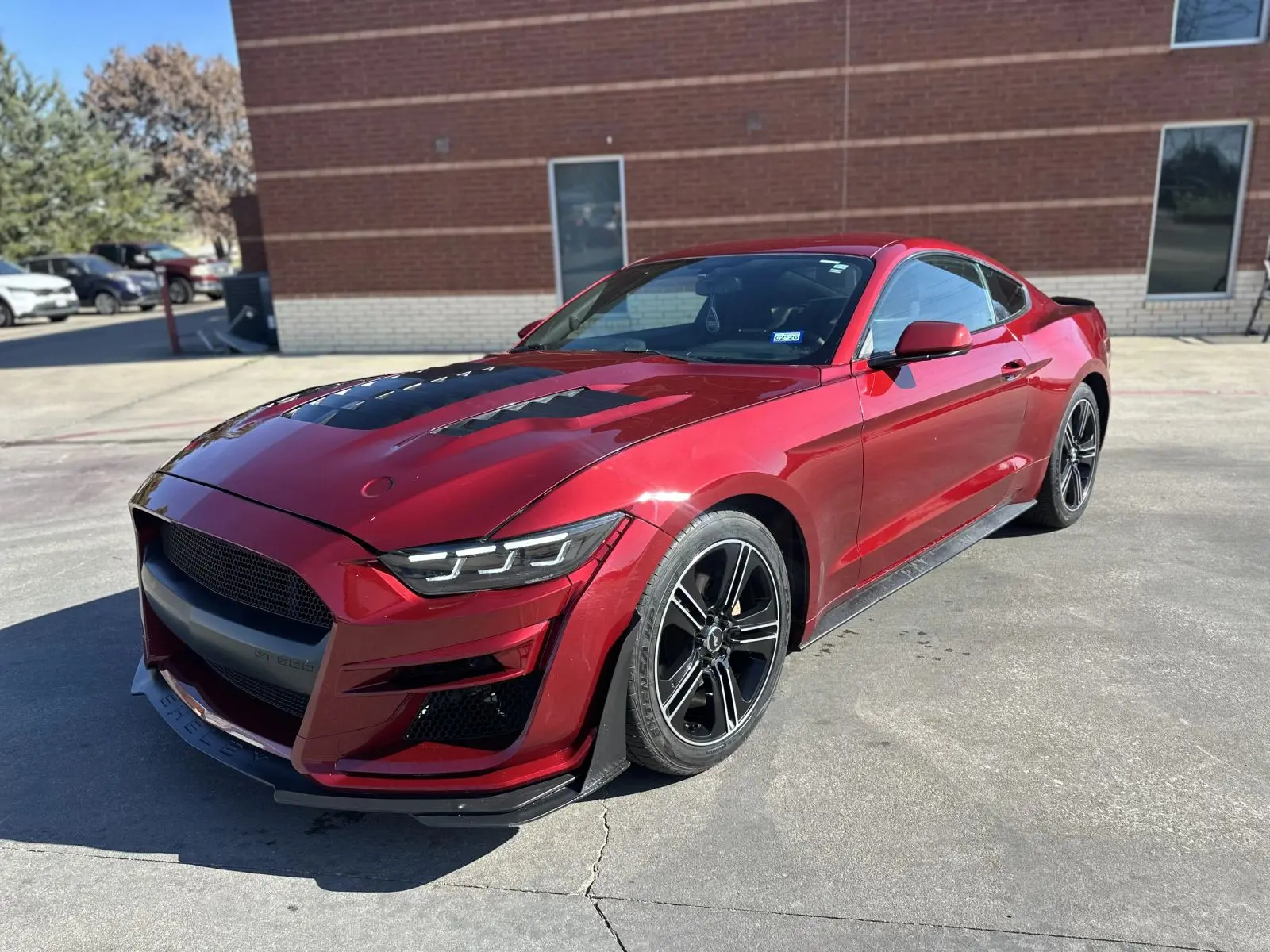 Red Mustang with an aftermarket hood and front splitter