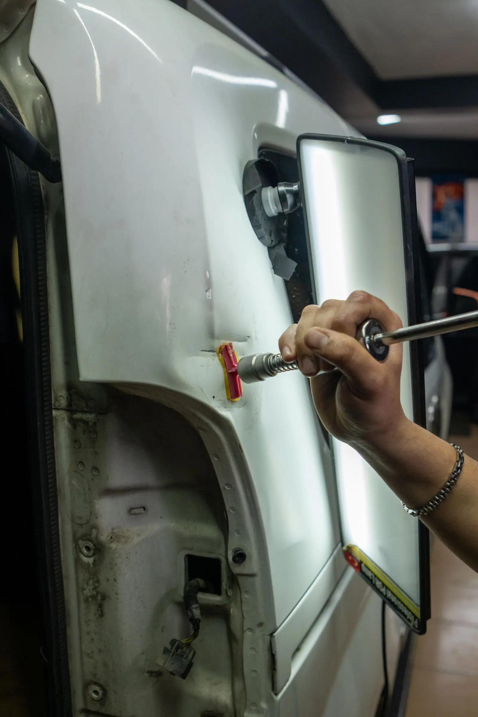 Technician pulling a dent from a door panel