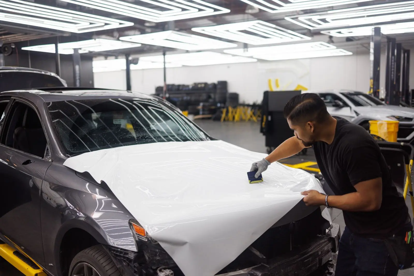 Installer applying a white vinyl wrap to a car hood